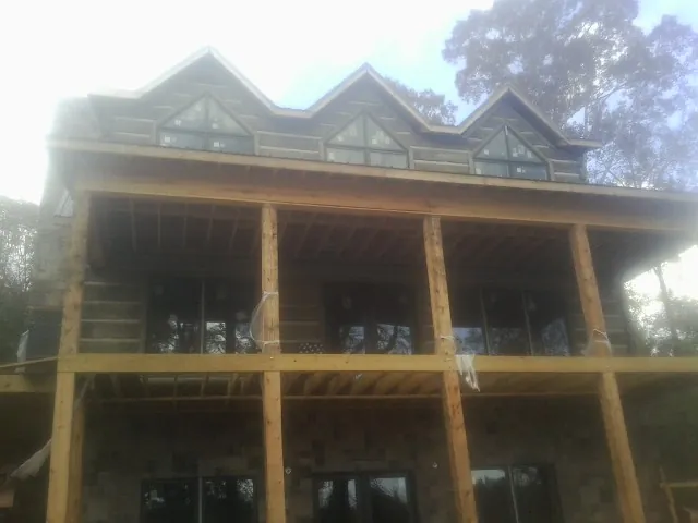 Dormers and porch framing on a large log home under construction — Roof Coating work by our crew in Fairmont